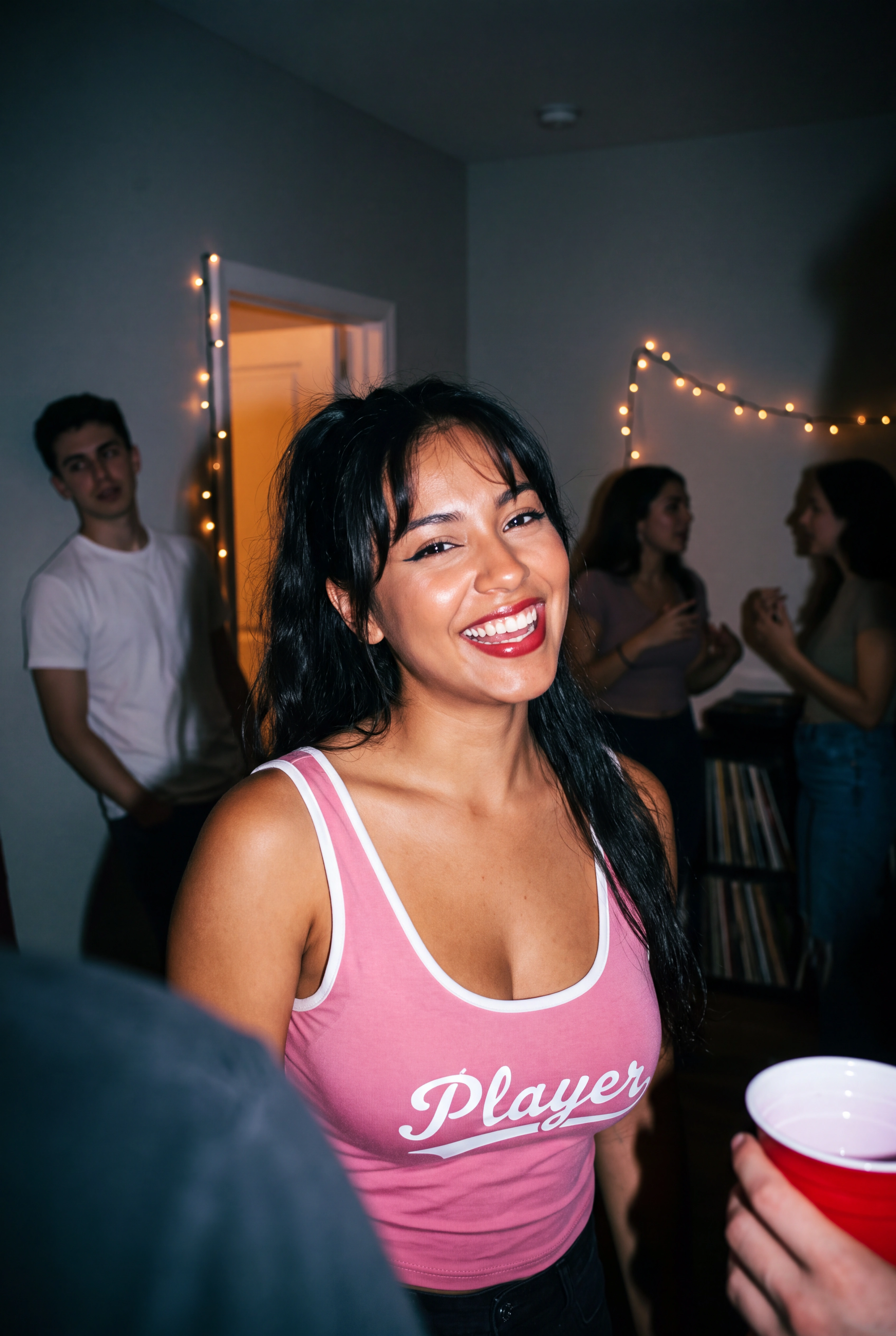High level description

    •A flash-lit polaroid-style close-up portrait of a young Puerto Rican woman mid-laugh at a late-night house party, wearing a pink 'Player' top, with out-of-focus partygoers